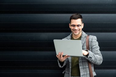 Ofis binasının önünde duran başarılı iş adamının portresi. Eğitimli bağımsız erkek takım lideri iş adamı siyah duvara karşı poz veriyor..