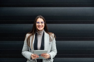 Ofis binasının önünde duran başarılı iş kadınının portresi. Eğitimli bağımsız kadın takım lideri iş adamı siyah duvara karşı poz veriyor..