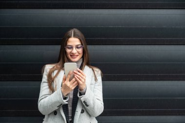 Ofis binasının önünde duran başarılı iş kadınının portresi. Eğitimli bağımsız kadın takım lideri iş adamı siyah duvara karşı poz veriyor..