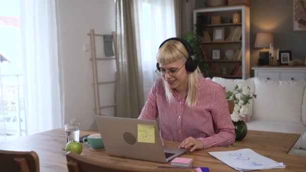 休憩中に友人や同僚とのビデオ通話のためにラップトップを使用して自宅のオフィスで働く若い成功したビジネス女性 女性ビジネスマンフリーランスの仕事 コンピュータ上の日常会議コール — ストック動画