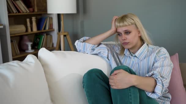 白种人悲伤的女人忧郁地坐在沙发上 年轻的女学生精神疲惫 情绪低落 感情障碍 独自坐在家里沉默 — 图库视频影像