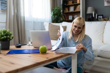 Young freelance business woman working at home on laptop as product strategy expert. Female expatriate remote work on internet on computer online for foreign company as web developer clipart