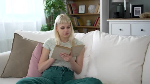 Młoda Szczęśliwa Niezależna Kobieta Czytająca Książkę Domu Siedząca Kanapie Ciesząca — Wideo stockowe