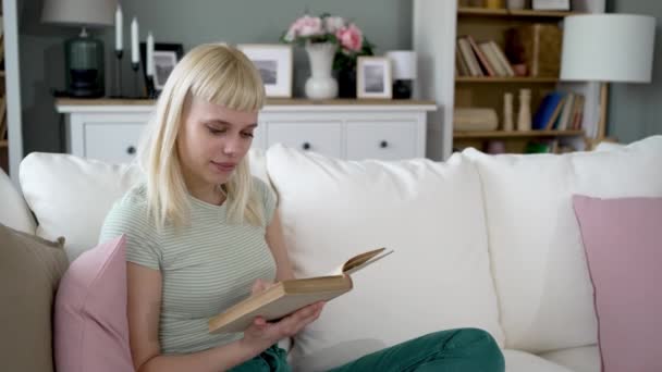 Młoda Szczęśliwa Niezależna Kobieta Czytająca Książkę Domu Siedząca Kanapie Ciesząca — Wideo stockowe