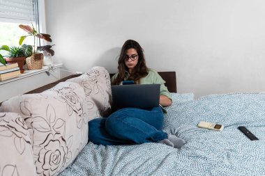 Ek iş para, ikinci iş konsepti. Öğrenci kredisini ödemek için internetten internet üzerinden çalışan genç bir üniversite öğrencisi, kira için para biriktiren, seyahat tatilinde ev videosundan çalışan bir kadın.