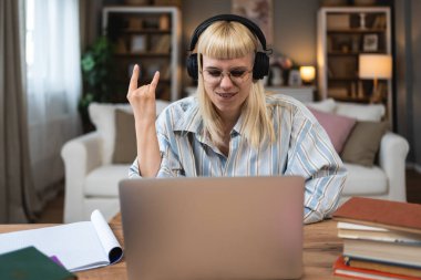 Genç hippi üniversite öğrencisi bir kadın ağır metal rock 'n roll dinliyor ya da kablosuz kulaklıkla ağır müzik dinliyor. Eğitim sınavı için kitap ve laptop kullanıyor ve evde öğrenim görüyor.