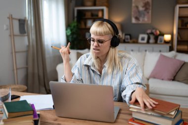 Genç hippi üniversite öğrencisi bir kadın ağır metal rock 'n roll dinliyor ya da kablosuz kulaklıkla ağır müzik dinliyor. Eğitim sınavı için kitap ve laptop kullanıyor ve evde öğrenim görüyor.