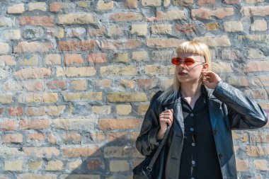 Genç, güzel, güçlü, bağımsız, asi, sarışın bir kadın. Punk müzik ve tarz hayranı pozu. Kendine güvenen Punk-Rock gençlik kültürü sokak tarzı konsepti. Havalı tavır. Farklı kavram.