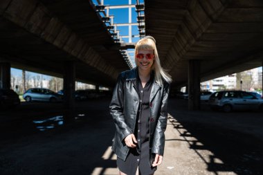 Genç, güzel, güçlü, bağımsız, asi, sarışın bir kadın. Punk müzik ve tarz hayranı pozu. Kendine güvenen Punk-Rock gençlik kültürü sokak tarzı konsepti. Havalı tavır. Farklı kavram.