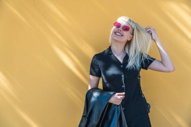 Genç, güzel, güçlü, bağımsız, asi, sarışın bir kadın. Punk müzik ve tarz hayranı pozu. Kendine güvenen Punk-Rock gençlik kültürü sokak tarzı konsepti. Havalı tavır. Farklı kavram.