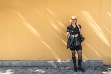 Genç, güzel, güçlü, bağımsız, asi, sarışın bir kadın. Punk müzik ve tarz hayranı pozu. Kendine güvenen Punk-Rock gençlik kültürü sokak tarzı konsepti. Havalı tavır. Farklı kavram.