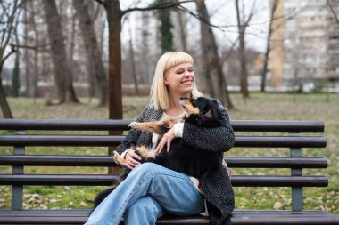 Genç nesil Z hippi kız, sokakta açlıktan kurtardığı evlatlık köpeği ile parkta oturuyor ve ona sevgi ve ilgi gösteriyor. Hayvan sever hayvanla eğleniyor..