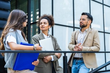 Üç genç iş adamı ofis binasının dışında bavul, dizüstü bilgisayar ve kayıt ile konuşurken birbirleriyle konuşuyorlar. Bir grup profesyonel işçi dışarıda iş ve planları tartışıyor.