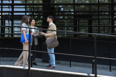 Üç genç iş adamı ofis binasının dışında bavul, dizüstü bilgisayar ve kayıt ile konuşurken birbirleriyle konuşuyorlar. Bir grup profesyonel işçi dışarıda iş ve planları tartışıyor.