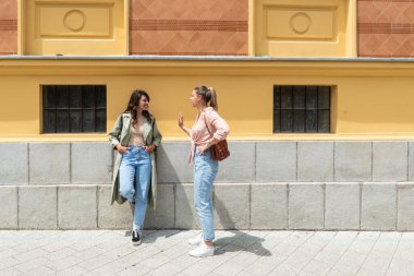 İki heyecanlı mutlu hippi sokakta birlikte yürüyen havalı kadınlar. Şehir caddesinde poz veren moda mankeni bir kadın. İyi tatiller, tasasız hafta sonları ve romantik tatiller, şık moda..