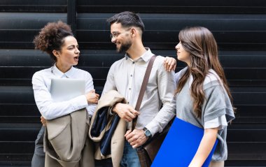 Kariyer sahibi zihniyeti. Bir grup genç iş adamı ofis binasının önünde. İşadamı ve kadınların kendilerini iş hayatında daha iyi fırsatlar için eğittiklerinden emin..