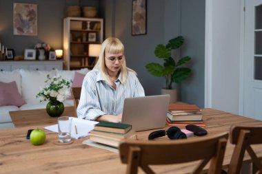 Kişisel gelişim. Genç, memnun öğrenci ya da iş kadını, bilgisayarla evden çalışıyor, kitaplardan öğreniyor, iş alanında yenilikler yapıyor ya da eğitim sınavlarına hazırlanıyor..
