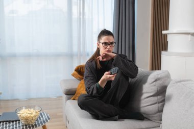 Tembellik konsepti. Genç tembel kadın boş zamanlarında kanepede uzanıp televizyon izliyor. İş kadınlarının hafta sonu aktiviteleri. Yapacak işi olmadığı ve kanepeden taşınma isteği olmadığı zaman..