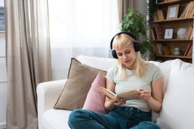 Genç milenyum kadını evinde kanepede oturmuş kablosuz kulaklıkla müzik dinliyor kitap okuyor hayatın ve özgürlüğün tadını çıkarıyor. Eğitimli üniversite öğrencisi kız dinleniyor ve karışık kasetle dinleniyor ve okuyor..