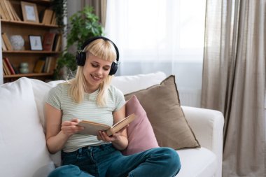 Genç milenyum kadını evinde kanepede oturmuş kablosuz kulaklıkla müzik dinliyor kitap okuyor hayatın ve özgürlüğün tadını çıkarıyor. Eğitimli üniversite öğrencisi kız dinleniyor ve karışık kasetle dinleniyor ve okuyor..