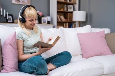 Genç milenyum kadını evinde kanepede oturmuş kablosuz kulaklıkla müzik dinliyor kitap okuyor hayatın ve özgürlüğün tadını çıkarıyor. Eğitimli üniversite öğrencisi kız dinleniyor ve karışık kasetle dinleniyor ve okuyor..