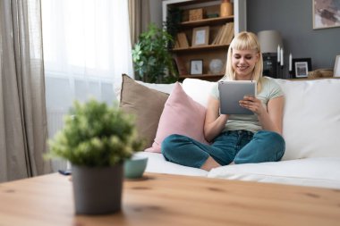 Genç milenyum kadını evinde dijital tabletle kanepede oturuyor, internette sörf yapıyor, online flört uygulamaları, e-postaları ya da sosyal medya kullanıcılarını okuyor, çevrimiçi mesajlaşıyor. Üniversite öğrencisi kadın teknolojisi