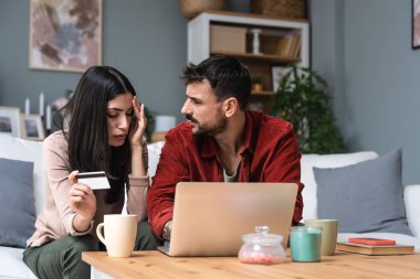 Genç çift evde dizüstü bilgisayar kullanarak oturuyor kredi kartı limiti ve bankacılık ile ilgili sorunları var. Gergin adam ve kadın, banka hesaplarındaki fazla parayı nerede harcadıklarını bulmaya çalışıyorlar..
