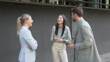 Bir grup başarılı iş adamı, işadamı ve iş kadını resmi giysiler içinde ofis binasının önünde durmuş iş hakkında tartışıyorlar. Harika mutlu gurbetçi şirket uzmanları bilgi alışverişinde bulunuyor.