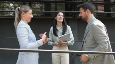 Bir grup başarılı iş adamı, işadamı ve iş kadını resmi giysiler içinde ofis binasının önünde durmuş iş hakkında tartışıyorlar. Harika mutlu gurbetçi şirket uzmanları bilgi alışverişinde bulunuyor.