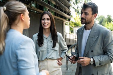 Bir grup başarılı iş adamı, işadamı ve iş kadını resmi giysiler içinde ofis binasının önünde durmuş iş hakkında tartışıyorlar. Harika mutlu gurbetçi şirket uzmanları bilgi alışverişinde bulunuyor.