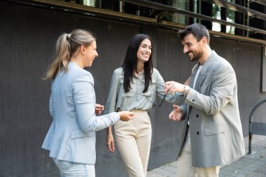 Bir grup başarılı iş adamı, işadamı ve iş kadını resmi giysiler içinde ofis binasının önünde durmuş iş hakkında tartışıyorlar. Harika mutlu gurbetçi şirket uzmanları bilgi alışverişinde bulunuyor.