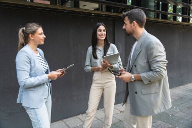 Bir grup başarılı iş adamı, işadamı ve iş kadını resmi giysiler içinde ofis binasının önünde durmuş iş hakkında tartışıyorlar. Harika mutlu gurbetçi şirket uzmanları bilgi alışverişinde bulunuyor.