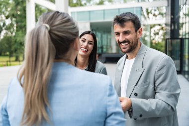 Bir grup başarılı iş adamı, işadamı ve iş kadını resmi giysiler içinde ofis binasının önünde durmuş iş hakkında tartışıyorlar. Harika mutlu gurbetçi şirket uzmanları bilgi alışverişinde bulunuyor.