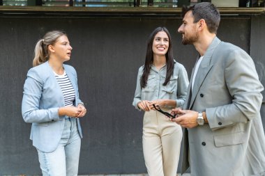 Bir grup başarılı genç iş adamı, pazarlama ve motivasyon liderleri, ofis binasının önünde durup çalışanlarla bir toplantı öncesinde danışmanlık yapıyorlar. Şirket konseptinde insan kaynakları iletişimi