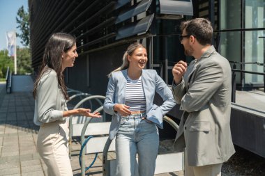 Bir grup başarılı genç iş adamı, pazarlama ve motivasyon liderleri, ofis binasının önünde durup çalışanlarla bir toplantı öncesinde danışmanlık yapıyorlar. Şirket konseptinde insan kaynakları iletişimi