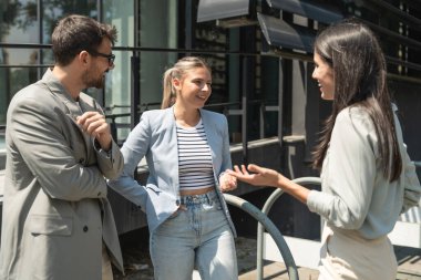 Bir grup başarılı genç iş adamı, pazarlama ve motivasyon liderleri, ofis binasının önünde durup çalışanlarla bir toplantı öncesinde danışmanlık yapıyorlar. Şirket konseptinde insan kaynakları iletişimi