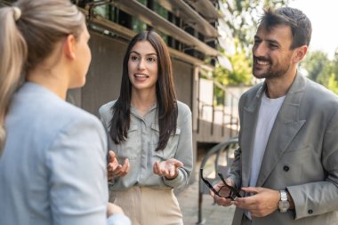 Bir grup başarılı genç iş adamı, pazarlama ve motivasyon liderleri, ofis binasının önünde durup çalışanlarla bir toplantı öncesinde danışmanlık yapıyorlar. Şirket konseptinde insan kaynakları iletişimi