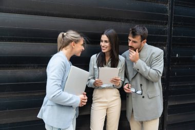 Bir grup başarılı genç iş adamı, pazarlama ve motivasyon liderleri, ofis binasının önünde durup çalışanlarla bir toplantı öncesinde danışmanlık yapıyorlar. Şirket konseptinde insan kaynakları iletişimi