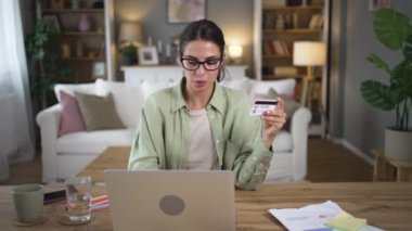 Kredi kartı ve dizüstü bilgisayarla internetten alışveriş yapan mutlu bir iş kadını evde oturuyor. İnternet bankacılığı ve ticaret alışveriş konsepti. Yemek siparişi vermek ya da online rezervasyon