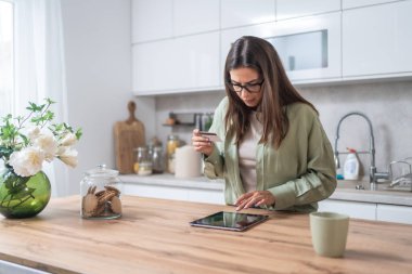 Basit bir yaşam. Mutfakta elinde kredi kartı olan genç bir kadın online ödemeyle veya dijital tabletle internetten alışveriş yapmakla sorun yaşıyor. Kadın bankacılık sorunları, aşırı harcamalar veya para hırsızlığı