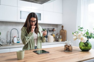 Basit bir yaşam. Mutfakta elinde kredi kartı olan genç bir kadın online ödemeyle veya dijital tabletle internetten alışveriş yapmakla sorun yaşıyor. Kadın bankacılık sorunları, aşırı harcamalar veya para hırsızlığı