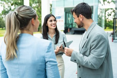 İş adamlarından oluşan bir ekip ofis binasının önünde konuşuyor. Personel toplantısı. Çalışanların motivasyon konuşması hakkında ofis çalışanlarını bilgilendirme toplantısı. İş adamı ve iş kadını fırsatları tartışıyor
