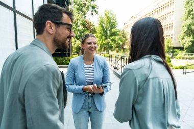 İş adamlarından oluşan bir ekip ofis binasının önünde konuşuyor. Personel toplantısı. Çalışanların motivasyon konuşması hakkında ofis çalışanlarını bilgilendirme toplantısı. İş adamı ve iş kadını fırsatları tartışıyor