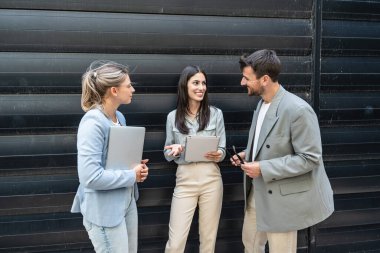 İş adamlarından oluşan bir ekip ofis binasının önünde konuşuyor. Personel toplantısı. Çalışanların motivasyon konuşması hakkında ofis çalışanlarını bilgilendirme toplantısı. İş adamı ve iş kadını fırsatları tartışıyor