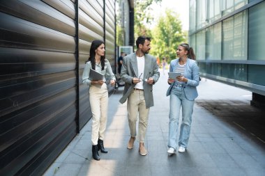 Genç iş adamları grup işkadını toplantılar arasında ofis binasından binaya yürür çalışanları daha iyi ve daha başarılı bir iş ve sunum için eğitirler.