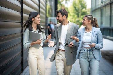 Genç iş adamları grup işkadını toplantılar arasında ofis binasından binaya yürür çalışanları daha iyi ve daha başarılı bir iş ve sunum için eğitirler.