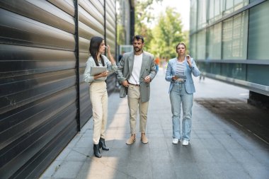 Genç iş adamları grup işkadını toplantılar arasında ofis binasından binaya yürür çalışanları daha iyi ve daha başarılı bir iş ve sunum için eğitirler.