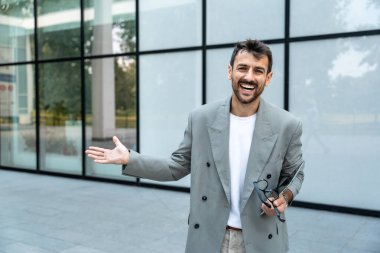Dijital tabletle ofis binasının önünde duran genç bir iş adamı takım lideri. Finansal bölgedeki iş yerinin dışında başarılı bir tasarımcının portresi. İş insanları