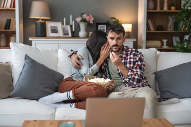 Çift dizüstü bilgisayarda korku filmi izlerken şok oldu. Kanepede oturup patlamış mısır yiyor. Yüzlerindeki korku, korku filmi ve kadın ve erkeğin hafta sonu aktiviteleri. Basit yaşam.