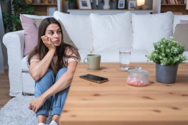 Depresyonda olan üzgün ve endişeli bir kadın yerde tek başına oturmuş hastaneden telefon bekliyor. Hasta kadın doktordan tıbbi sonuçlar bekliyor. Sağlık ve İlaç